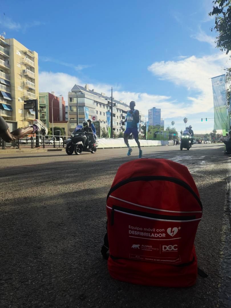 Mochila «Equipo móvil con desfibrilador» junto al circuito del Medio Maratón Valencia mientras pasa un corredor